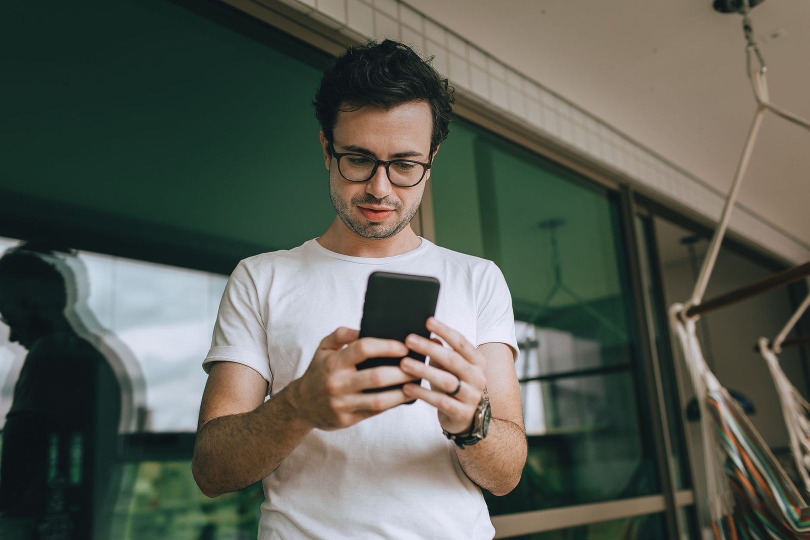 Man i vit tröja läser på sin smartphone, som en digital påminnelse