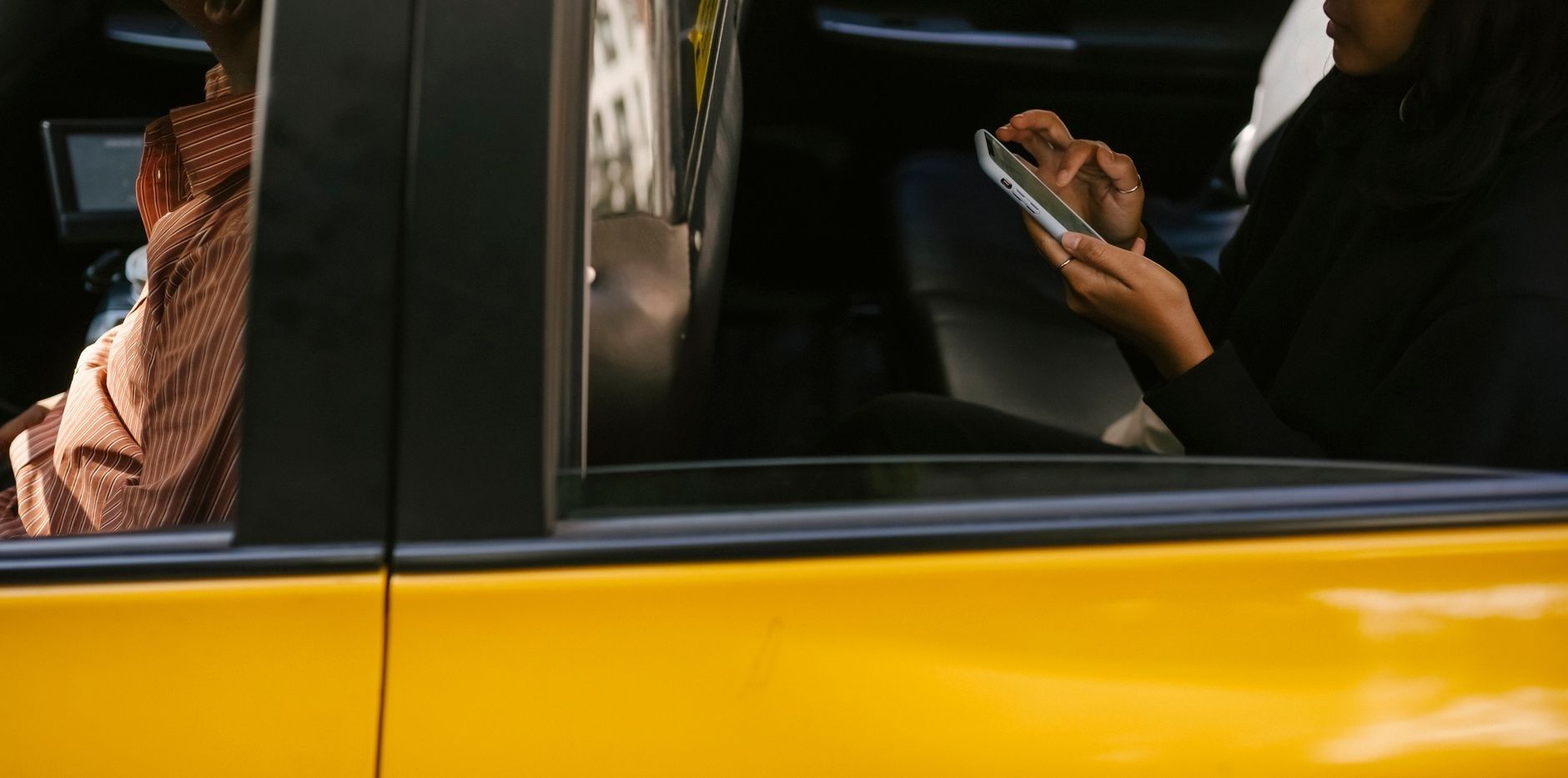 Person använder en mobil i en gul bil under en resa